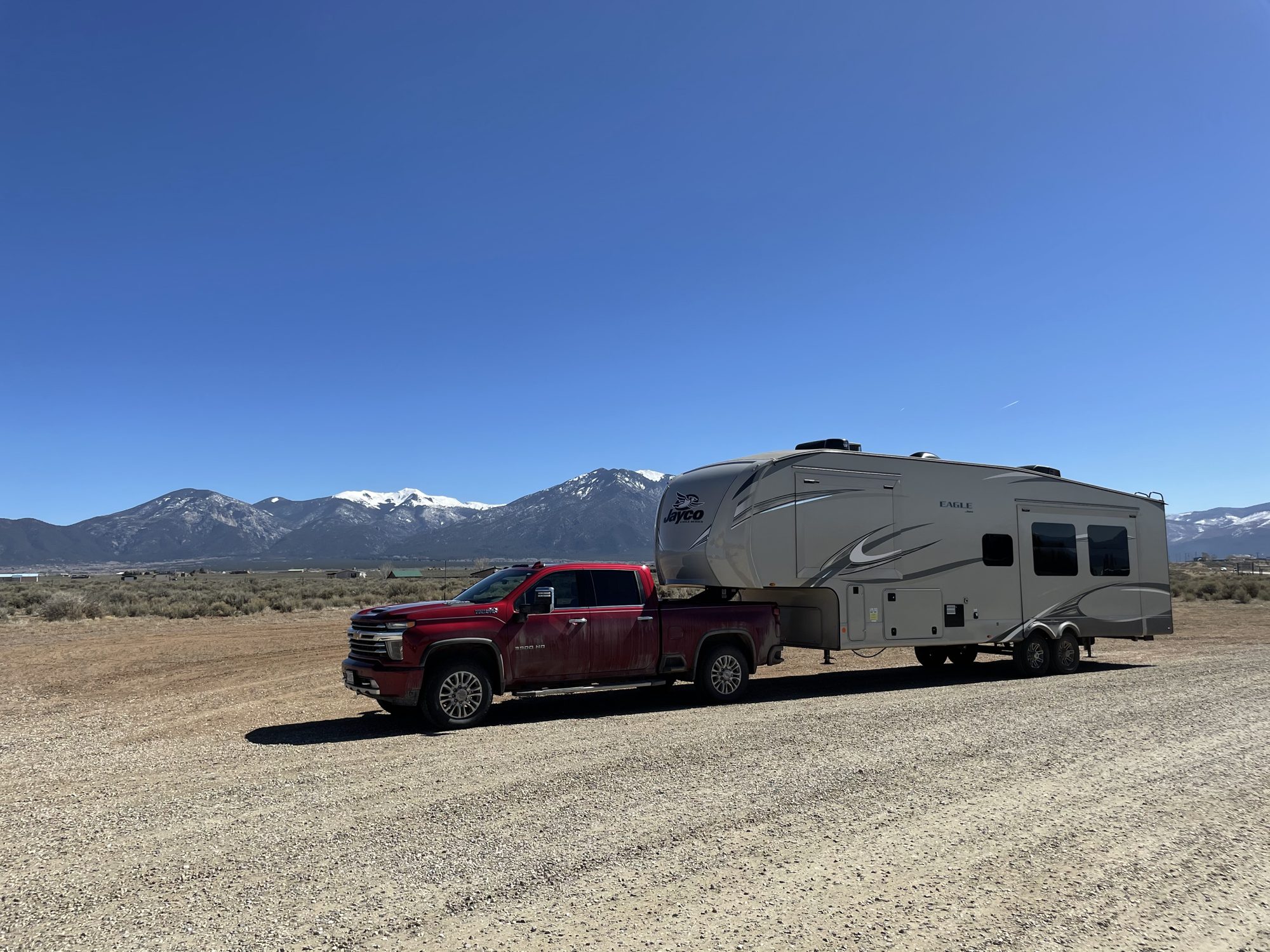 A pickup truck and fifth-wheel trailer parked at dusk.